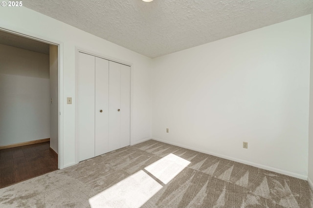 unfurnished bedroom featuring a closet, carpet flooring, a textured ceiling, and baseboards