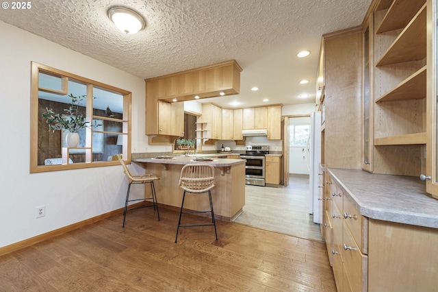 kitchen featuring under cabinet range hood, light wood-type flooring, range with two ovens, a peninsula, and open shelves