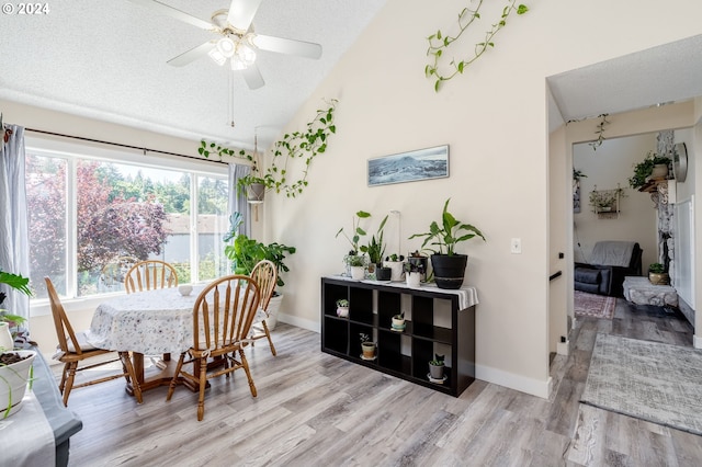 dining room with lofted ceiling, a textured ceiling, ceiling fan, and light wood-type flooring