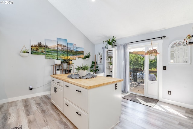 kitchen with a center island, light hardwood / wood-style floors, wooden counters, lofted ceiling, and white cabinets