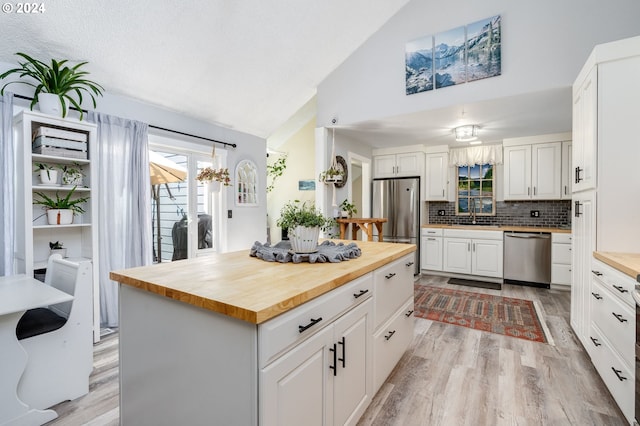 kitchen with stainless steel appliances, white cabinets, and wooden counters