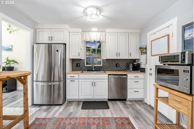 kitchen featuring sink, decorative backsplash, white cabinetry, and appliances with stainless steel finishes