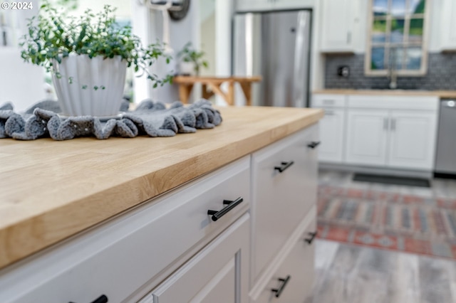 kitchen with sink, white cabinetry, dishwasher, stainless steel refrigerator, and backsplash