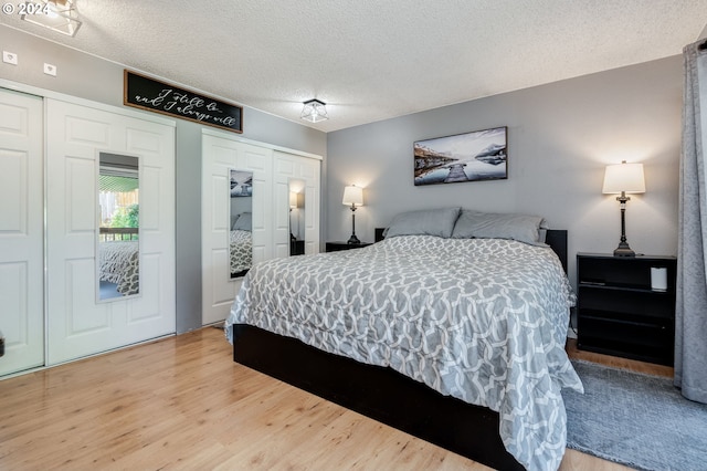 bedroom featuring a textured ceiling, multiple closets, and hardwood / wood-style floors