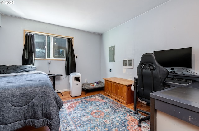 bedroom with electric panel and hardwood / wood-style flooring