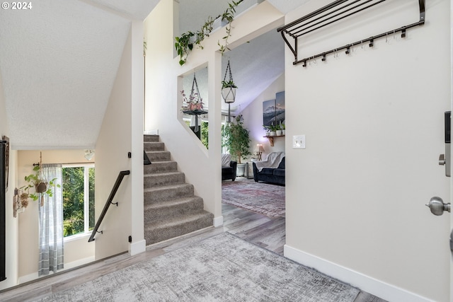 entrance foyer featuring lofted ceiling, light wood-type flooring, and a textured ceiling