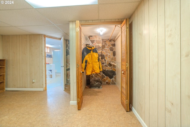 corridor with a drop ceiling and wooden walls