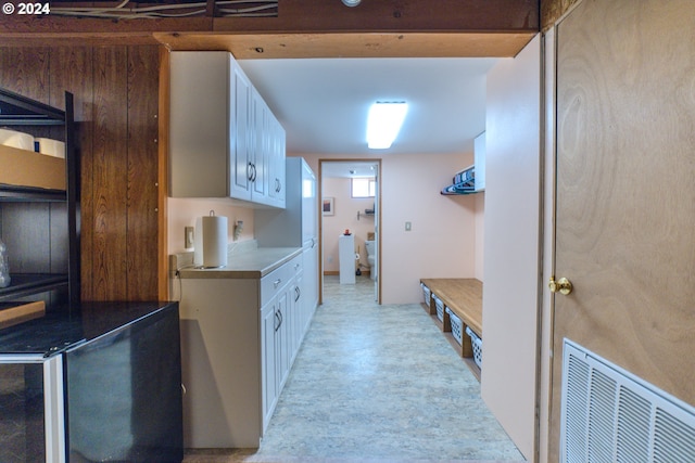 kitchen featuring wooden walls and white cabinetry