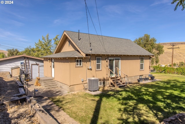 rear view of property featuring a garage, an outdoor structure, central air condition unit, and a yard