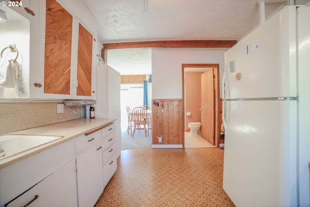 kitchen featuring white refrigerator and white cabinetry