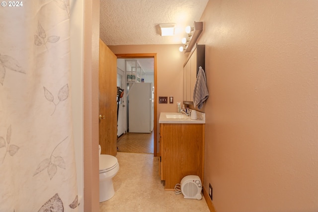 bathroom with a textured ceiling, vanity, and toilet