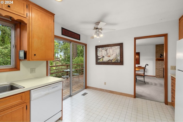 kitchen with white dishwasher, light carpet, ceiling fan, and sink