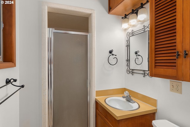 bathroom featuring a shower with door, vanity, and toilet