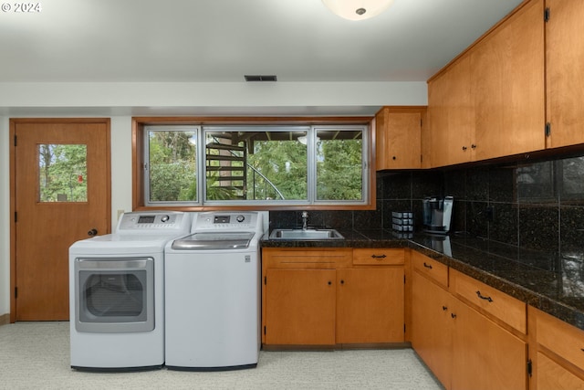 clothes washing area with separate washer and dryer and sink