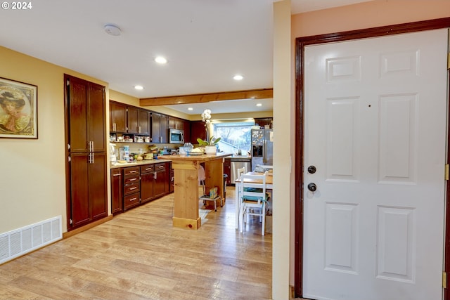 kitchen featuring a breakfast bar, appliances with stainless steel finishes, light wood-type flooring, and a center island