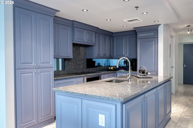 kitchen featuring sink, tasteful backsplash, black cooktop, dark stone counters, and a center island with sink