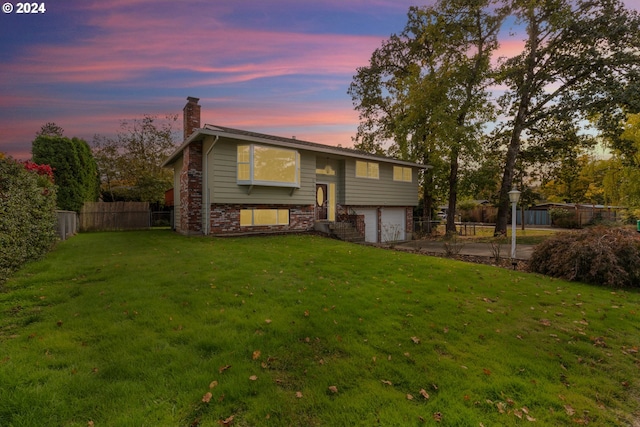 split foyer home featuring a garage and a lawn