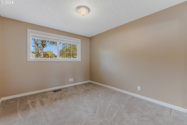 empty room with a textured ceiling and light colored carpet