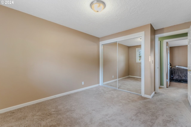 unfurnished bedroom with light carpet, a closet, and a textured ceiling