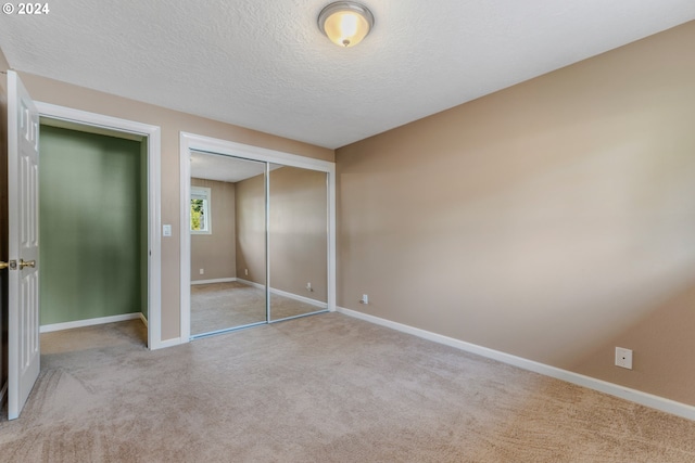 unfurnished bedroom featuring light carpet, a textured ceiling, and a closet