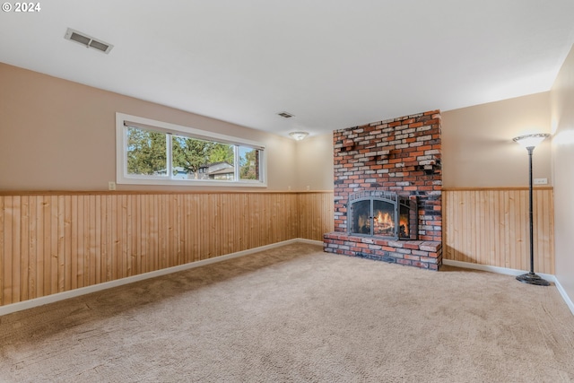 unfurnished living room featuring carpet floors, wooden walls, and a brick fireplace