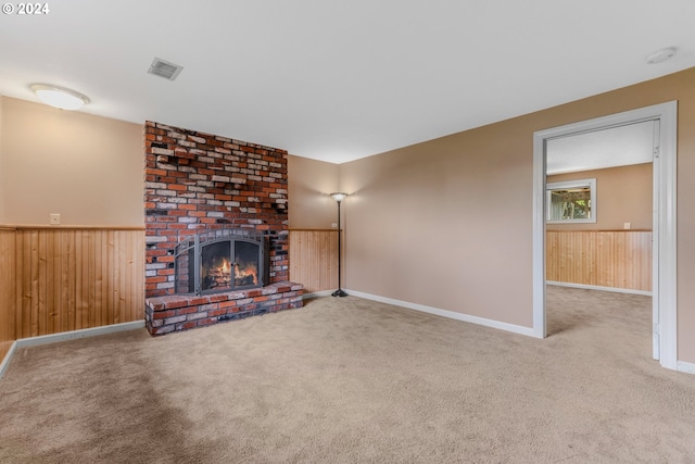 unfurnished living room featuring carpet flooring, wooden walls, and a fireplace