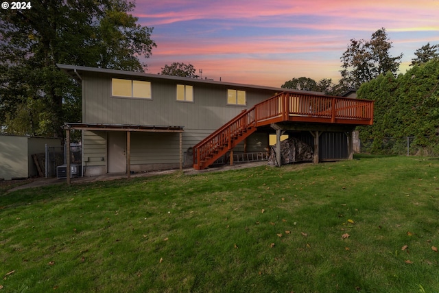 back house at dusk with a deck and a lawn