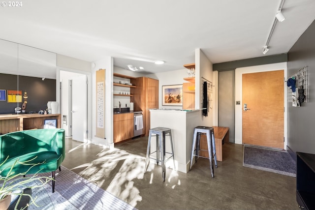 kitchen with a kitchen bar, rail lighting, sink, stainless steel dishwasher, and kitchen peninsula