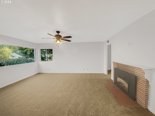 unfurnished living room with a brick fireplace, carpet floors, and ceiling fan