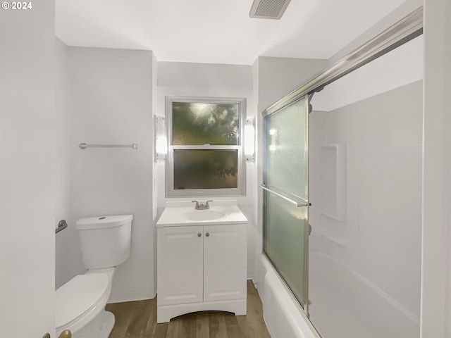 full bathroom with vanity, toilet, hardwood / wood-style floors, and shower / bath combination with glass door