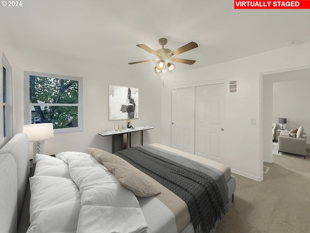 bedroom featuring light colored carpet, ceiling fan, and a closet