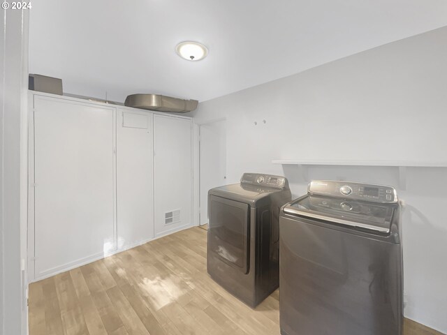 clothes washing area featuring light hardwood / wood-style flooring and washer and dryer