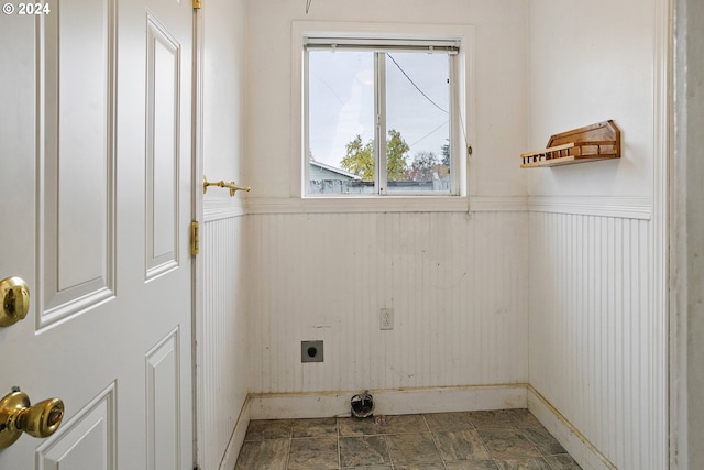 laundry room with a wainscoted wall, stone finish flooring, laundry area, and electric dryer hookup