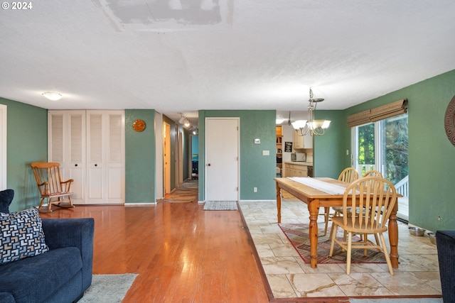 dining room with light hardwood / wood-style flooring, a chandelier, and a textured ceiling