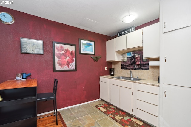 kitchen featuring white cabinetry, tile flooring, backsplash, and sink