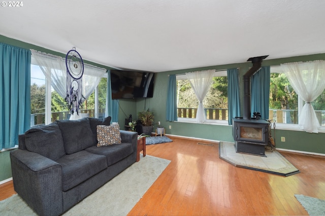 living room featuring a wood stove, plenty of natural light, and hardwood / wood-style flooring