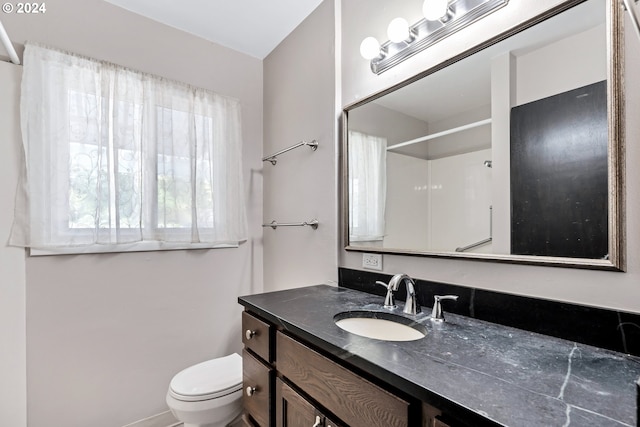 bathroom with vanity, toilet, and a shower