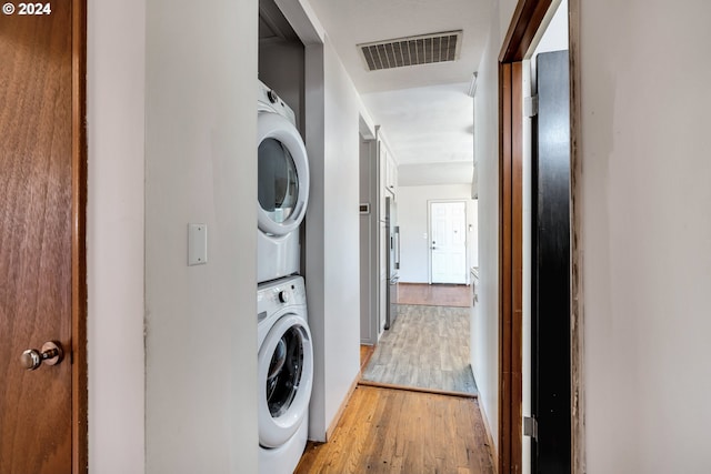 clothes washing area featuring hardwood / wood-style flooring and stacked washer / drying machine