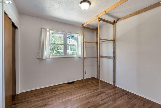 unfurnished bedroom with hardwood / wood-style flooring, a textured ceiling, and a closet