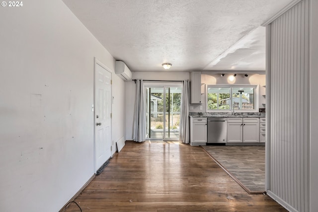 kitchen featuring sink, an AC wall unit, dark wood-type flooring, and stainless steel dishwasher