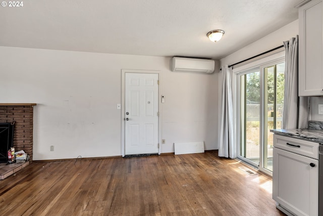 interior space featuring an AC wall unit, dark hardwood / wood-style floors, and a stone fireplace