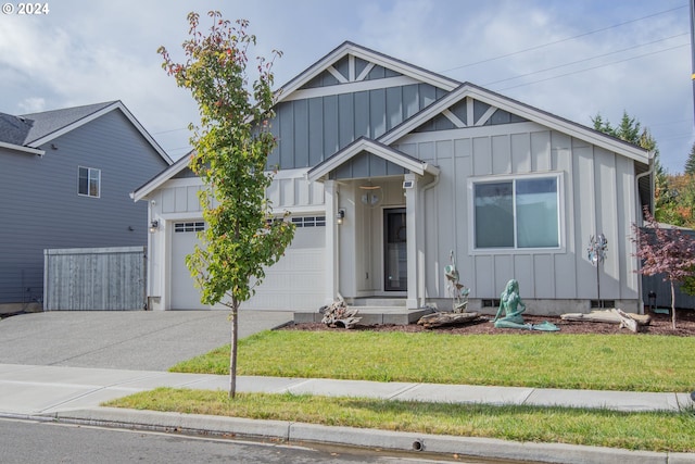 view of front of house with a front lawn, a garage, board and batten siding, and driveway