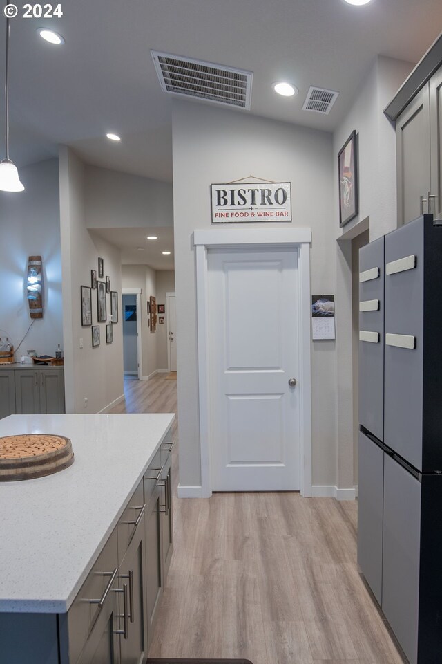 kitchen featuring stainless steel appliances, a center island, light hardwood / wood-style flooring, and decorative light fixtures