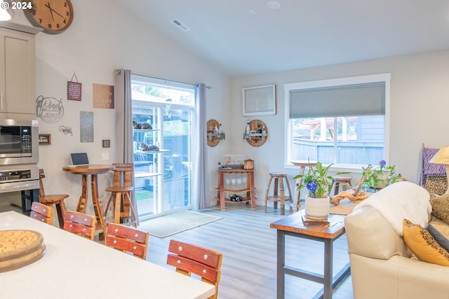 living area featuring visible vents, lofted ceiling, and wood finished floors