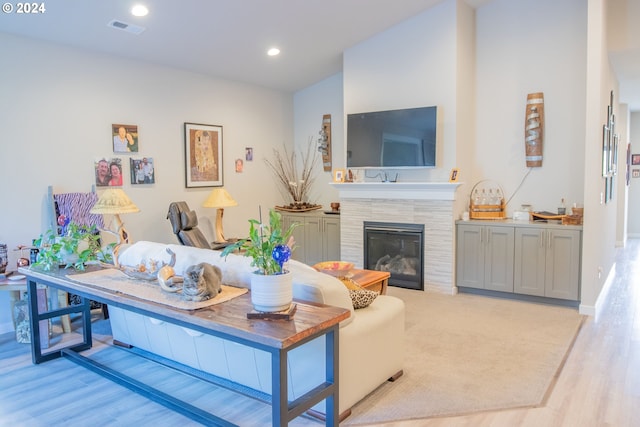 living area featuring baseboards, visible vents, recessed lighting, a tile fireplace, and light wood-style floors