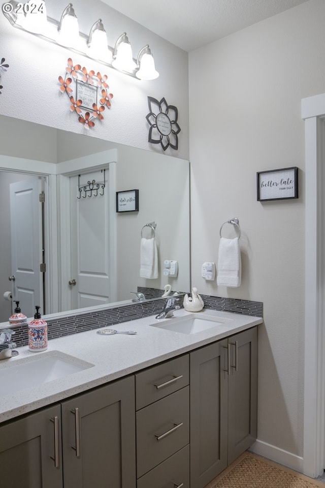 bathroom with a sink, speckled floor, baseboards, and double vanity