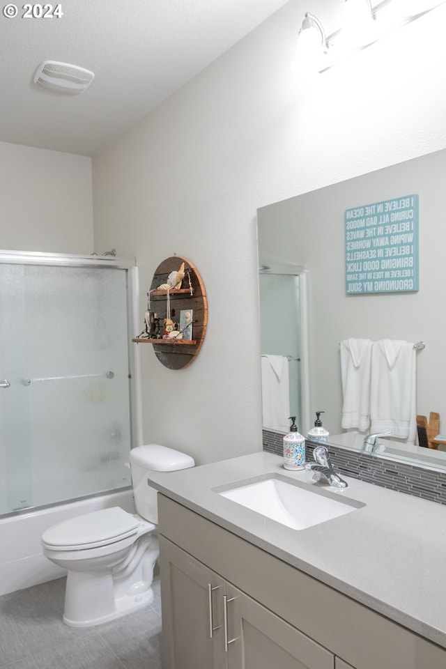 bathroom featuring tile patterned flooring, visible vents, toilet, shower / bath combination with glass door, and vanity