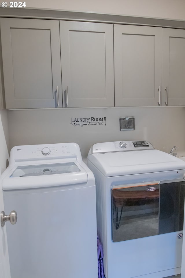 clothes washing area featuring cabinet space and washer and clothes dryer