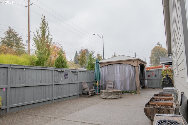 view of patio with a fire pit, a fenced backyard, a storage shed, and an outdoor structure