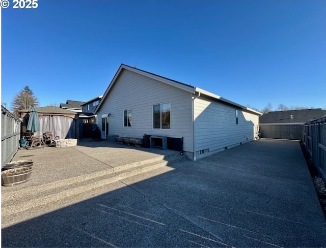 back of property featuring a fenced backyard, an outdoor structure, a storage shed, and a patio